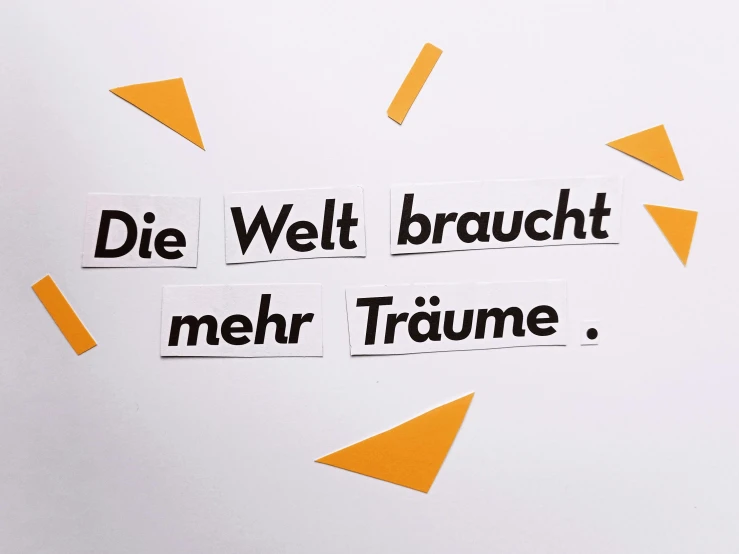 a piece of paper with the words die wet braucht mehr trume written on it, trending on pexels, arbeitsrat für kunst, background image, multi-part, dunce, bright ”