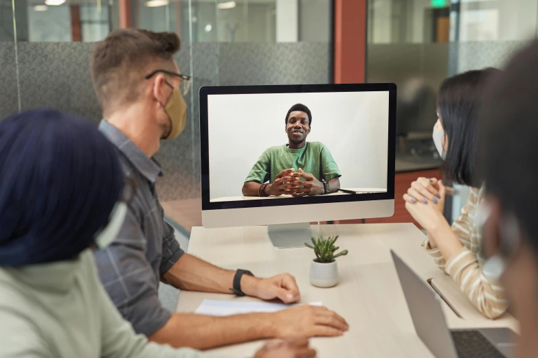 a group of people sitting at a table in front of a computer screen