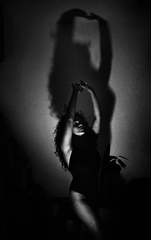a black and white photo of a woman's shadow, inspired by Carrie Mae Weems, unsplash, dancer of the underworld, ffffound, with claws, divine ray over her head