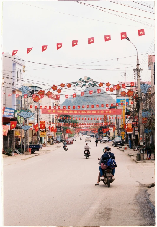 a group of people riding motorcycles down a street, prayer flags, dang my linh, instagram story, red banners