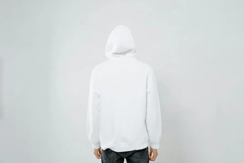 a man in a white hoodie standing in front of a white wall, facing away, listing image, full product shot, facing front