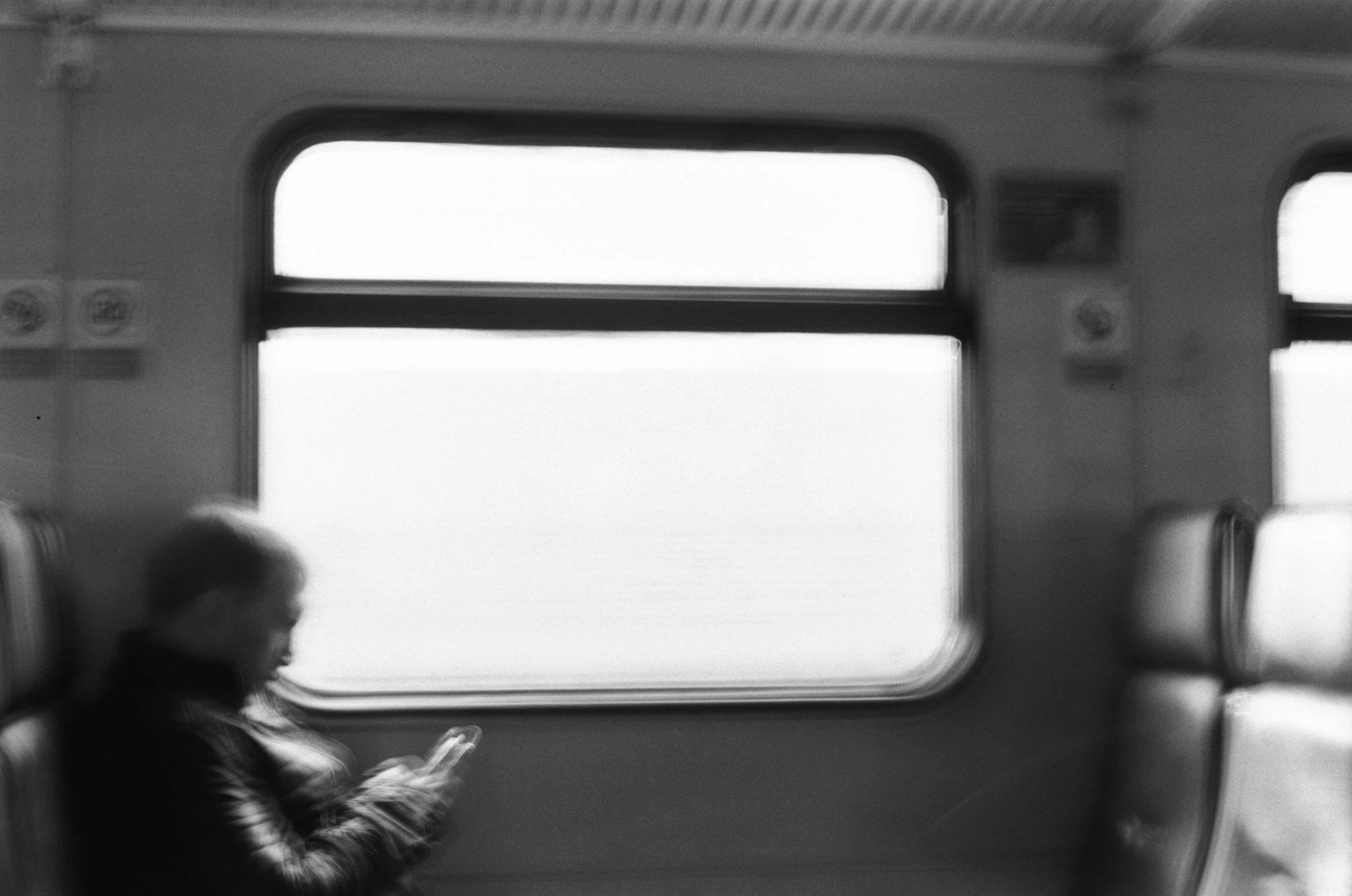 a black and white photo of a person sitting on a train, postminimalism, cell phone photo, istván sándorfi, soft blur, sofya emelenko