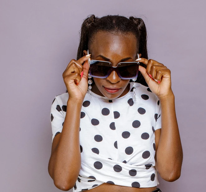 a woman holding a pair of sunglasses in front of her face, trending on pexels, polka dot, african woman, wearing a cropped top, shot in the photo studio