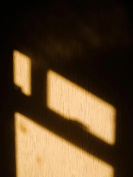 a cat laying on top of a bed next to a window, inspired by Arnold Newman, unsplash, light and space, shadow of catholic church cross, 8 k. volumetric lighting. dark, golden hour closeup photo, abstract detail