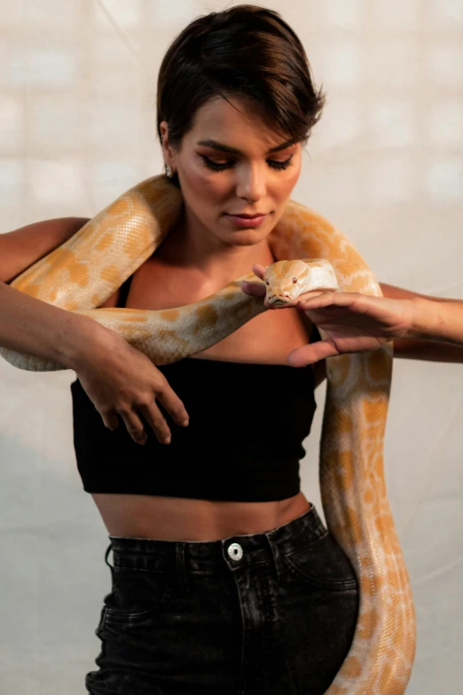 a woman holding a snake over her shoulder, trending on pexels, wearing a crop top, 2 animals, studio photoshoot, large)}]