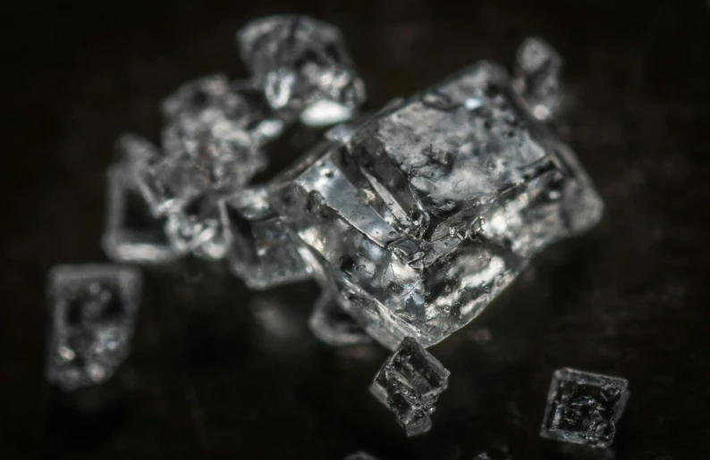 a pile of ice cubes sitting on top of a table, a macro photograph, by Adam Marczyński, pexels, ashes crystal, detailed photo 8 k, molecular gastronomy, ground - level medium shot