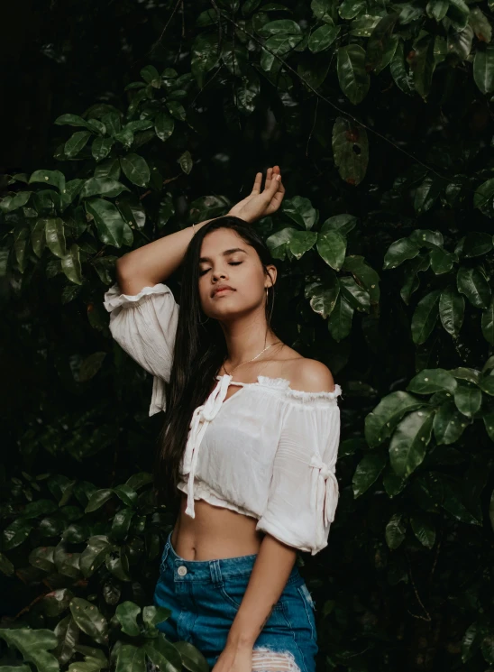 a woman standing in front of a bush with her hands on her head, inspired by Elsa Bleda, trending on pexels, isabela moner, croptop, indoor picture, ( ( ( kauai ) ) )