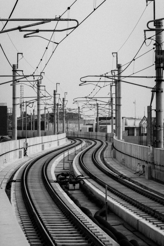a black and white photo of a train track, electricity archs, in tokio, tehran, random circular platforms