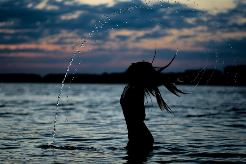 a woman standing in the water with her hair blowing in the wind, by Jan Tengnagel, pexels contest winner, summer evening, crystallized human silhouette, girl with plaits, thirst