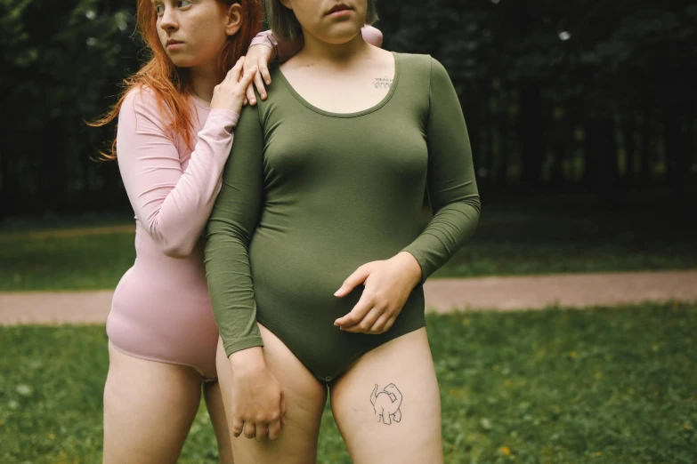 a couple of women standing next to each other, a tattoo, inspired by Elsa Bleda, trending on pexels, renaissance, green swimsuit, patricia piccinini, a park, round thighs