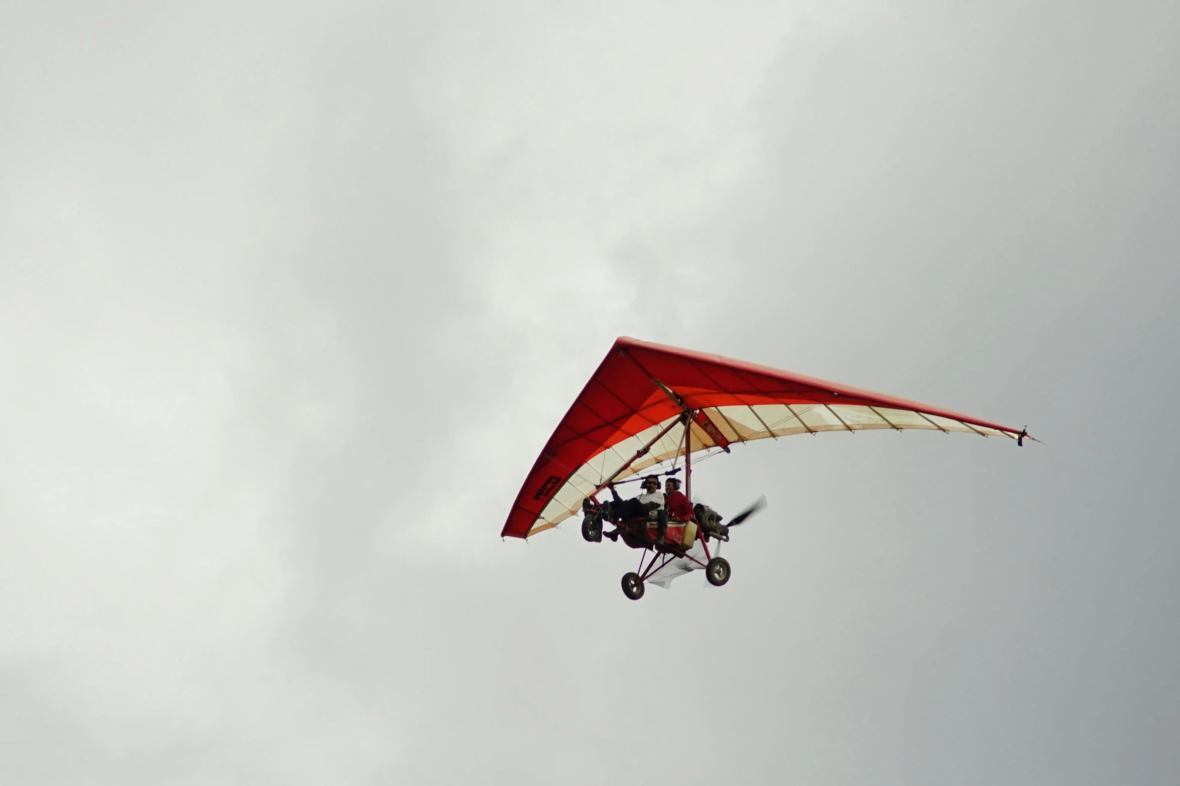 a red and white hang glider flying through a cloudy sky, a picture, pexels contest winner, buggy, flying vehicles, low quality photo, concert photo