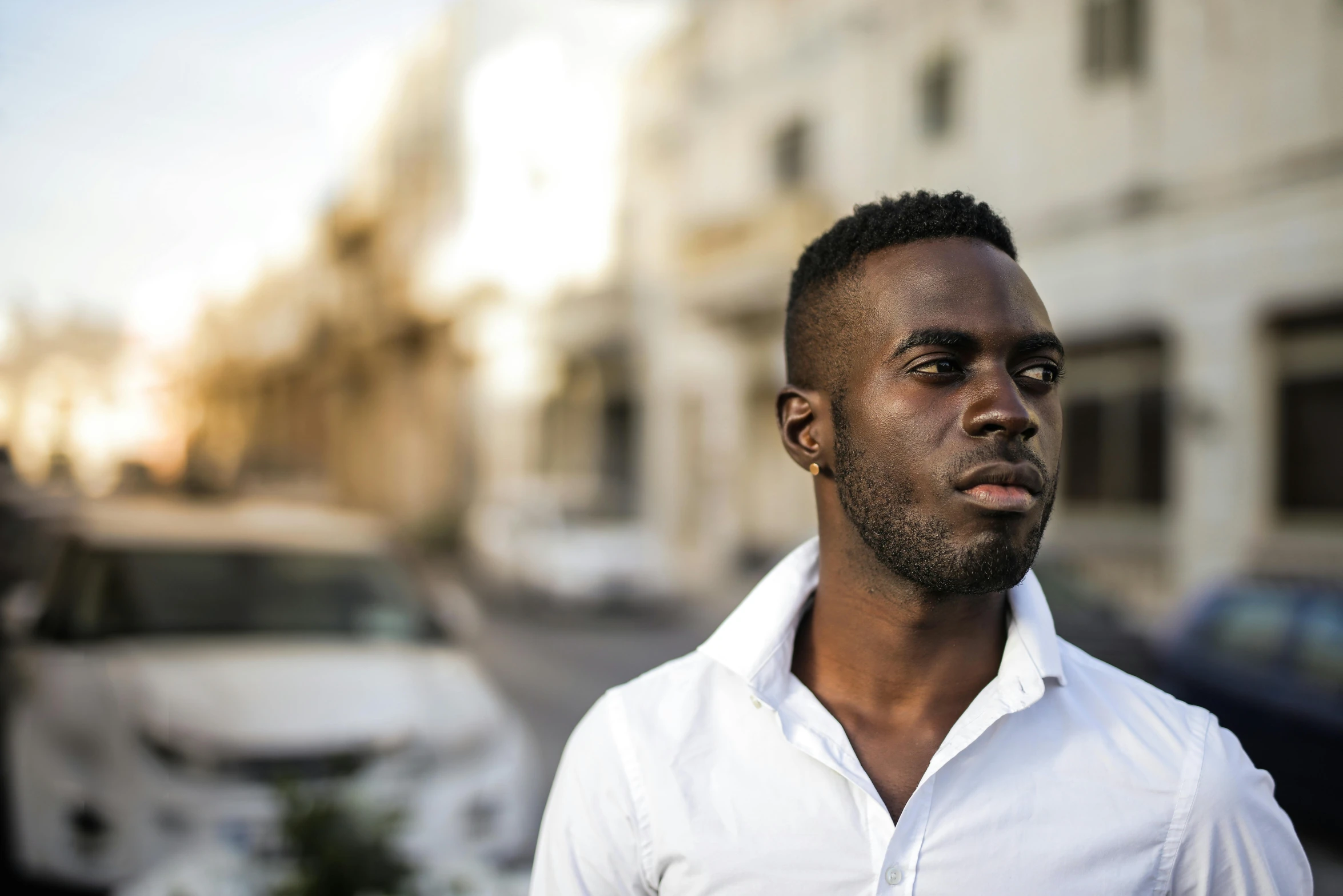 a man in a white shirt standing on a city street, pexels contest winner, les nabis, dark skin tone, headshot profile picture, young greek man, black
