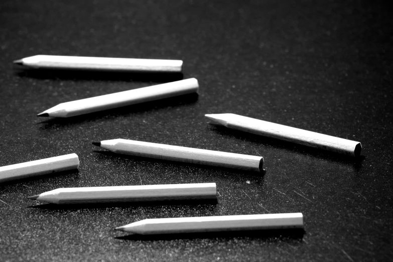a group of pencils sitting on top of a table, a charcoal drawing, platinum jewellery, monochrome contrast bw, cuts, close-up product photo