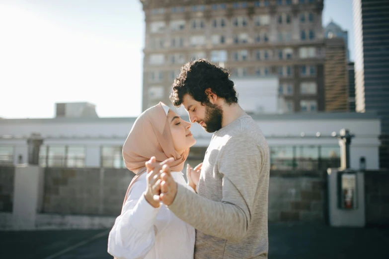 a man and a woman standing next to each other, pexels contest winner, hurufiyya, making out, background image, muslim, on rooftop