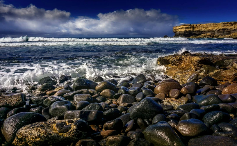 a large body of water sitting on top of a rocky beach, by Greg Rutkowski, pexels contest winner, ocean swells, marsden, australian beach, deep colours. ”