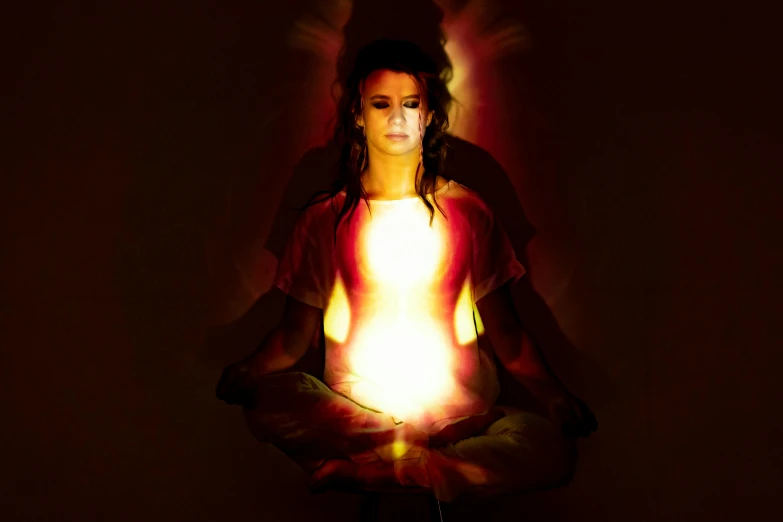 a woman sitting in the middle of a meditation pose, by Kristian Zahrtmann, light and space, eyes are glowing red lightbulbs, promo image, chakras, body made of fire