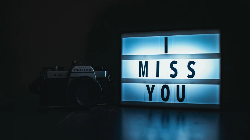 a light box that says i miss you next to a camera, by Julia Pishtar, unsplash, avatar image, romantic mood, slightly pixelated, richard pearce