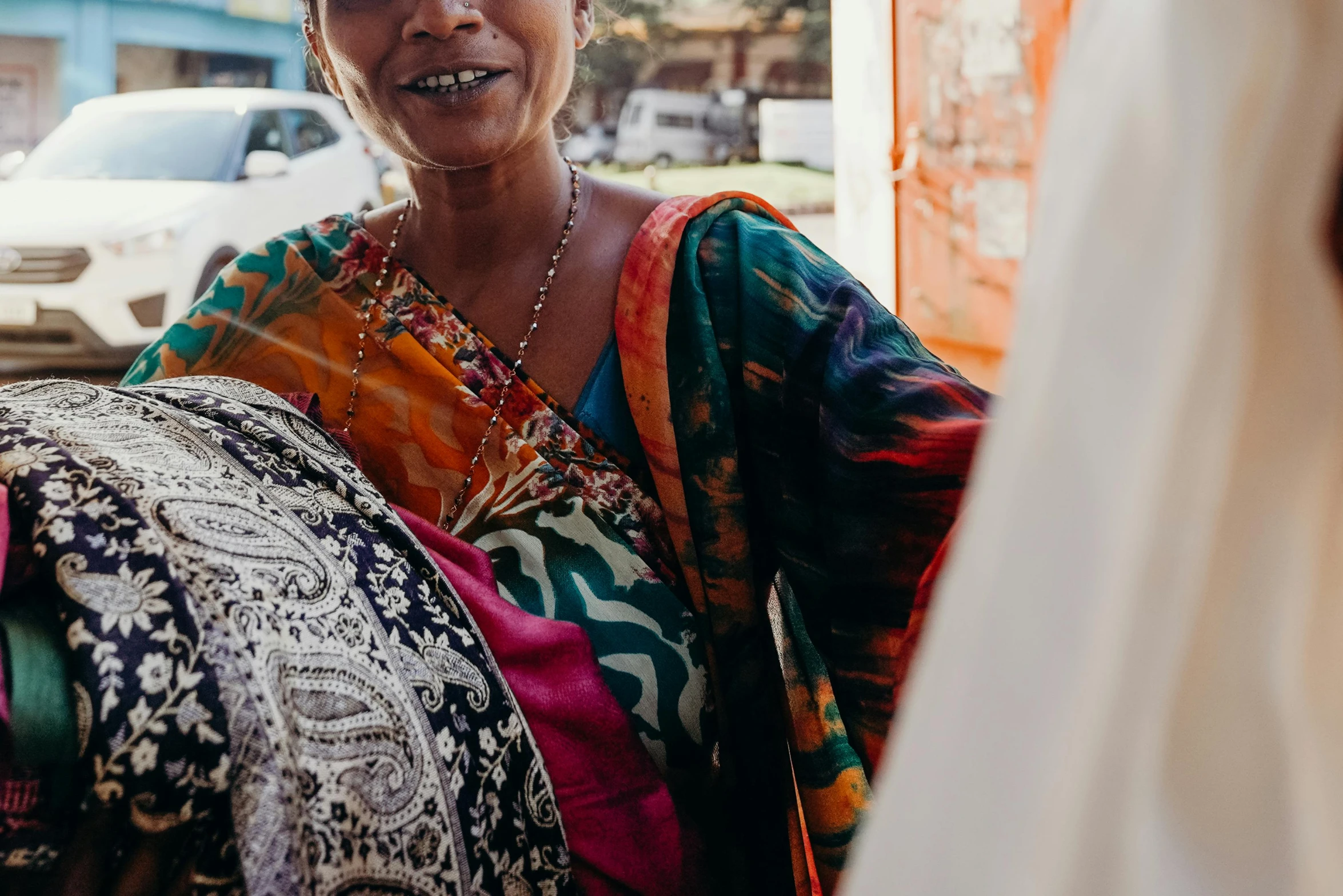 a woman in a colorful sari smiles at the camera, trending on unsplash, people shopping, batik, woman holding another woman, close up details