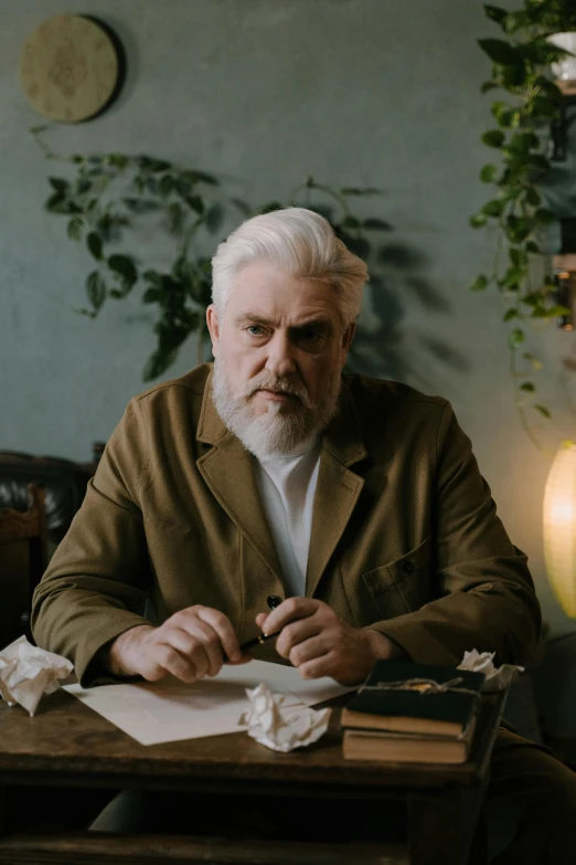 a man sitting at a table writing on a piece of paper, a character portrait, inspired by Karl Gerstner, pexels contest winner, greybeard, monia merlo, grumpy [ old ], tom burke