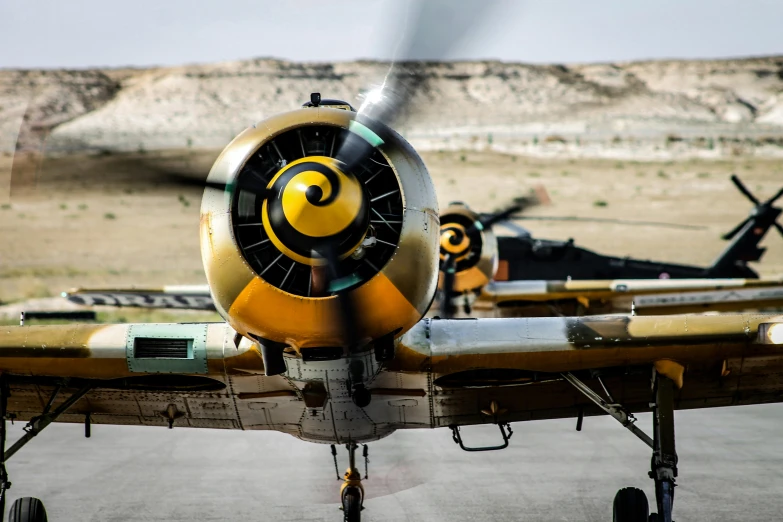 a propeller plane sitting on top of an airport tarmac, a colorized photo, by Arnie Swekel, pexels contest winner, striking eyes, fighter jets, closeup photograph, afar