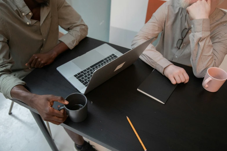 a couple of people sitting at a table with a laptop, trending on pexels, gray men, sitting on a mocha-colored table, workers, bottom angle