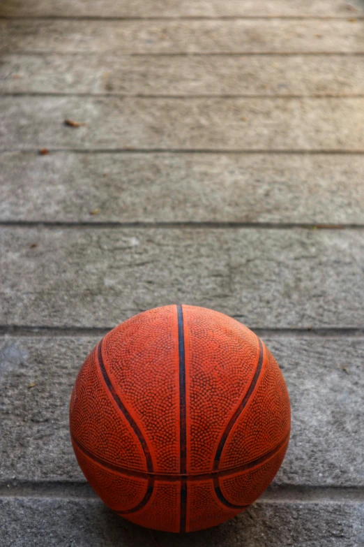 a basketball sitting on top of a wooden floor, on ground