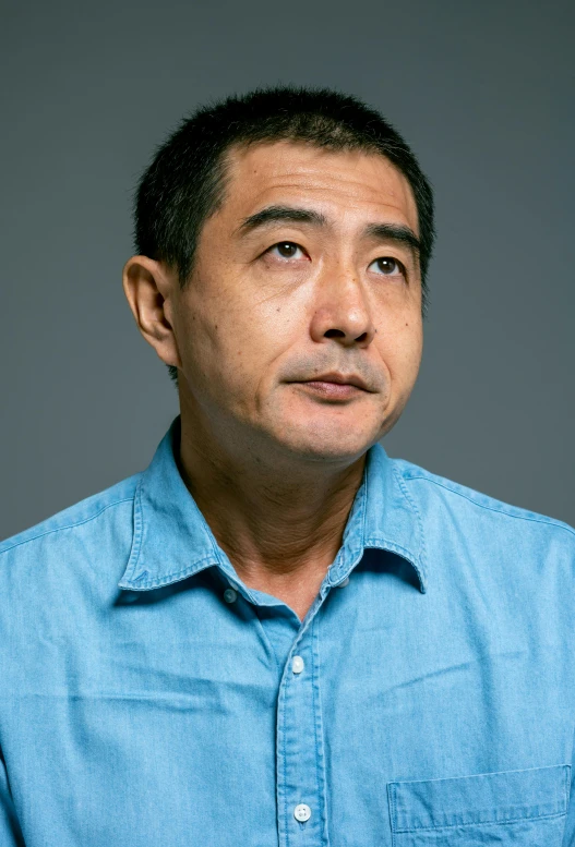 a close up of a person wearing a blue shirt, shin hanga, looking towards the camera, middle aged man, asian man, on grey background