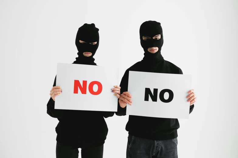 two people in masks holding signs that say no, a poster, by Nina Hamnett, pexels, bank robbery movies, black on white background, background image, zentai suit