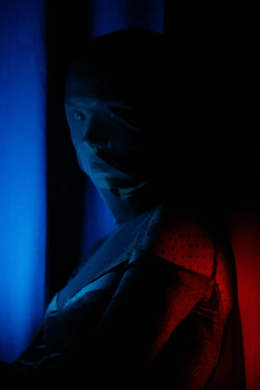 a close up of a person in a dark room, by Adam Marczyński, red and blue garments, ((blue)), light show, frank moth