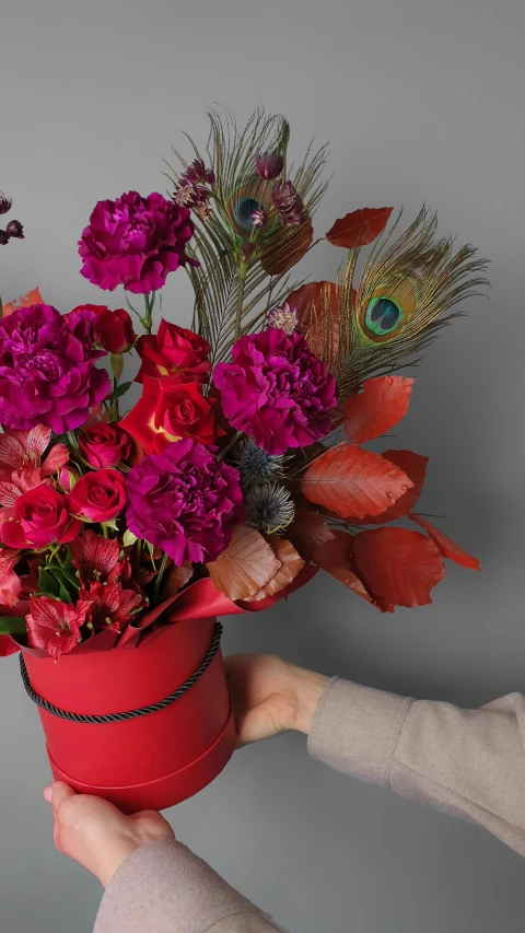 a person holding a red bucket filled with flowers, inspired by François Boquet, maroon metallic accents, magenta colours, festive, on grey background