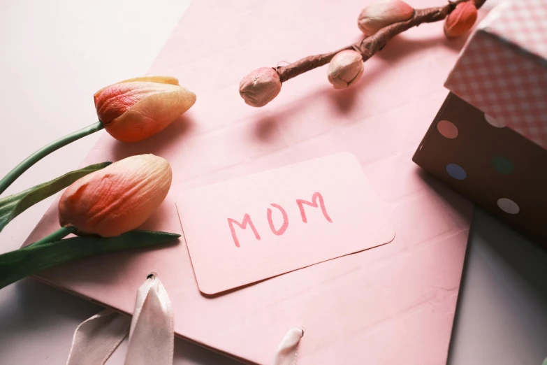 a mother's day card next to a bouquet of tulips, by Carey Morris, pexels contest winner, sitting on a mocha-colored table, jovana rikalo, ribbon, uwu