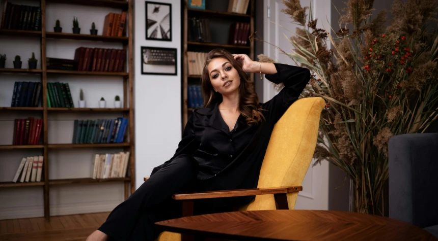 a woman sitting in a chair in a living room, a portrait, by Julia Pishtar, pexels contest winner, black luxurious suit, moleksandra shchaslyva, librarian, young business woman