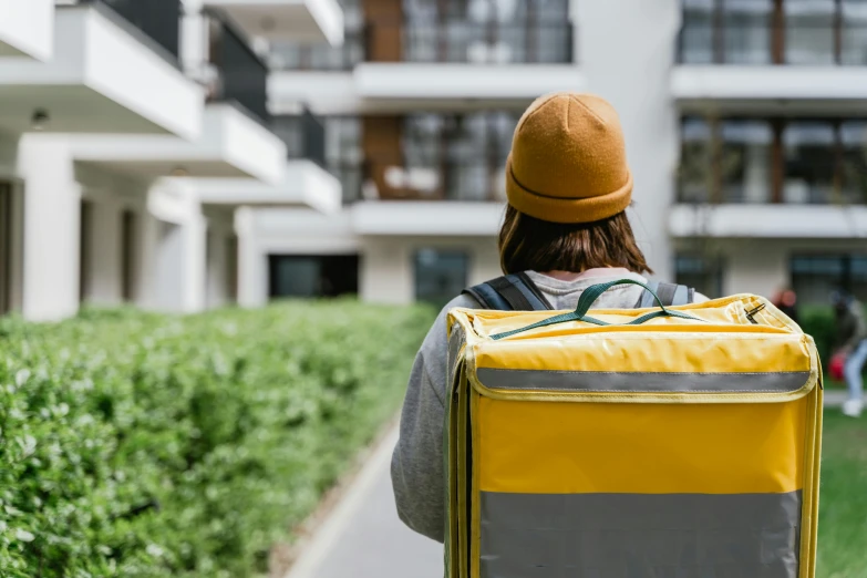 a person with a backpack walking down a sidewalk, yellow and green, milkman, delivering parsel box, avatar image