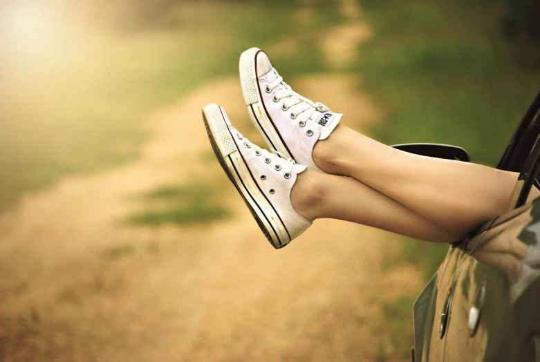 a woman's legs hanging out the window of a car, trending on pixabay, photorealism, wearing white sneakers, converse, sun is shining, laying on the ground