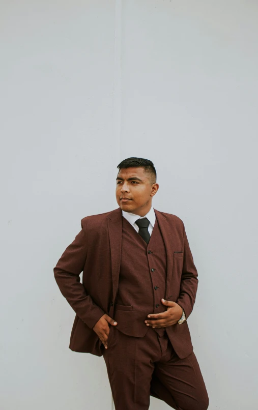 a man in a suit standing in front of a wall, an album cover, by Robbie Trevino, unsplash, maroon and white, indian, brown suit vest, profile image