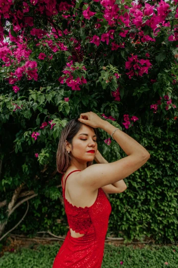 a woman in a red dress posing for a picture, by Robbie Trevino, pexels contest winner, with soft bushes, bralette, bougainvillea, julia fuentes