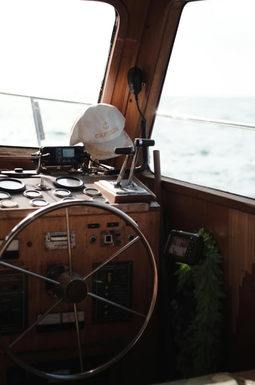 a close up of a steering wheel on a boat, a portrait, by Jan Tengnagel, unsplash, low quality photo, captain hat, a wooden, coast