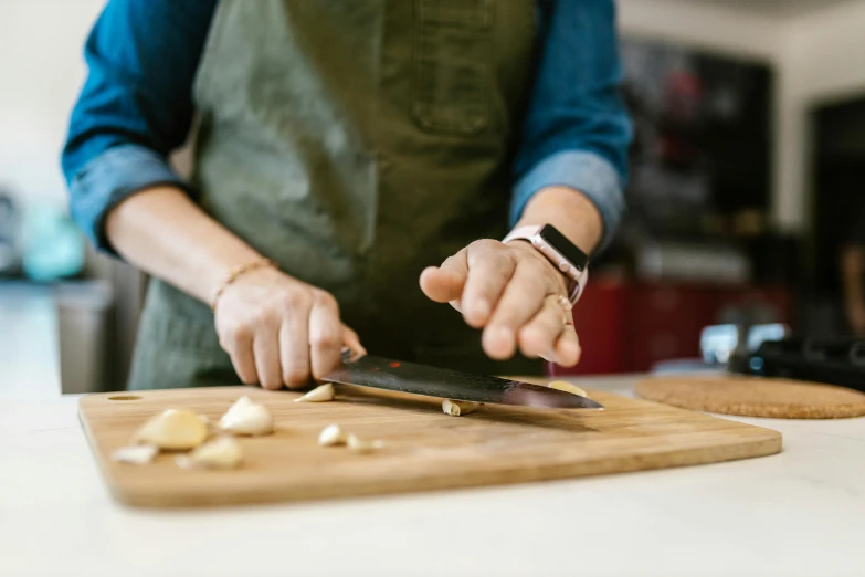 a woman chopping garlic on a cutting board, by Joe Bowler, pexels, plated arm, in a workshop, lachlan bailey, panoramic shot