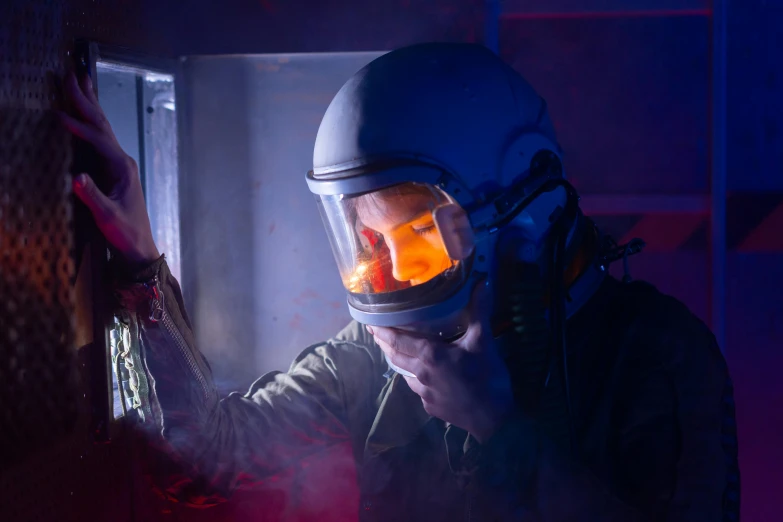 a close up of a person wearing a helmet, pexels contest winner, nuclear art, air force jumpsuit, in a darkly lit laboratory room, on set, smoke grenades