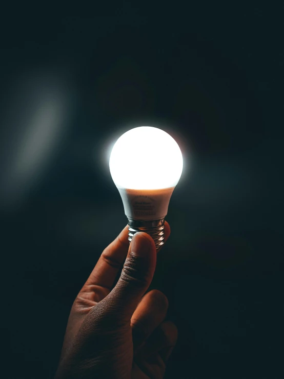 a person holding a light bulb in their hand, pexels contest winner, light and space, cool white color temperature, out in the dark, brightly lit!