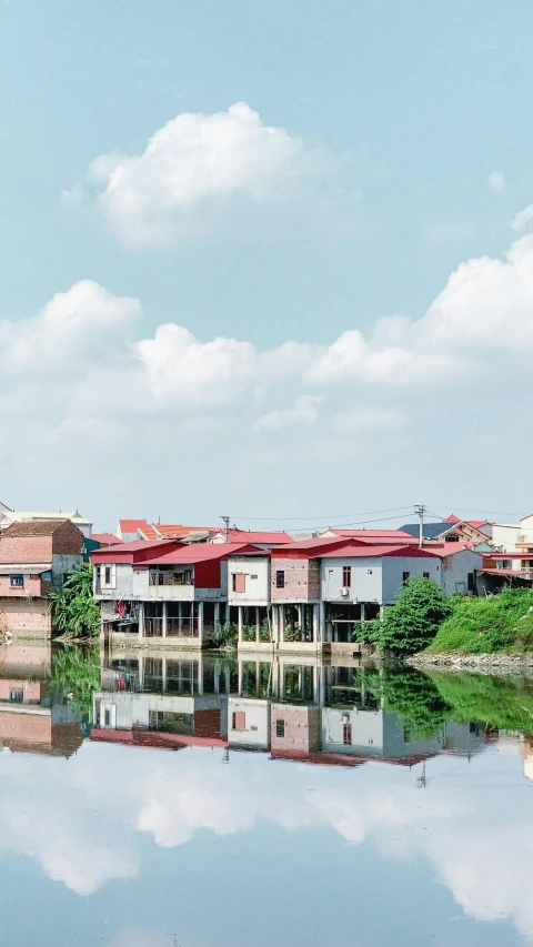 a body of water with buildings in the background, by Basuki Abdullah, unsplash, photorealism, of a small village with a lake, profile image, phuoc quan, housing architecture