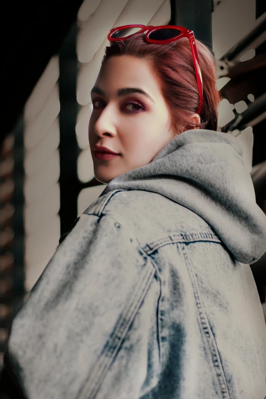 a woman wearing a denim jacket and sunglasses, a colorized photo, inspired by Elsa Bleda, trending on pexels, photorealism, wearing a grey hooded sweatshirt, red hair and attractive features, dua lipa, confident looking