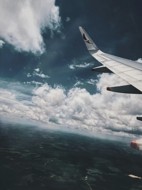 the wing of an airplane flying in the sky, by Christen Dalsgaard, pexels contest winner, happening, gloomy skies, video footage, tourist photo, trending on vsco