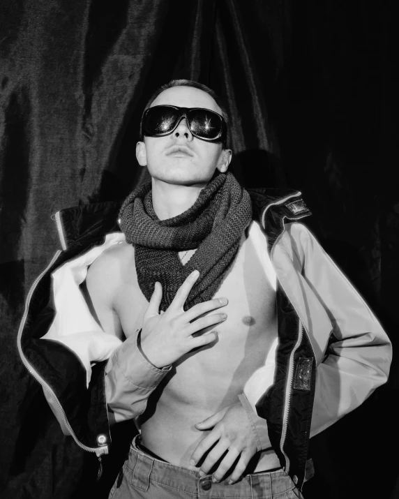 a black and white photo of a shirtless man, a black and white photo, inspired by Taro Yamamoto, unsplash, bauhaus, stylish coat for a rave, sunglasses and a scarf, attractive androgynous humanoid, taken in night club