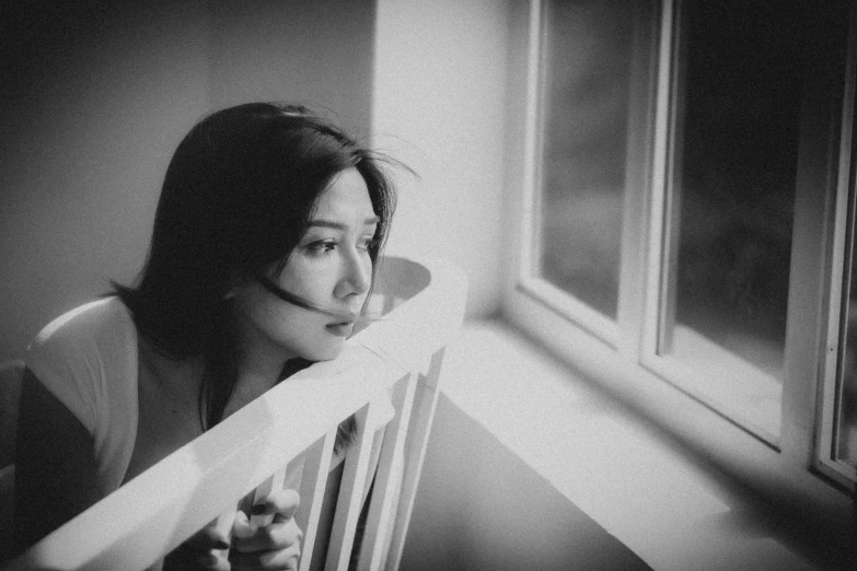 a black and white photo of a woman looking out a window, by Mathias Kollros, pexels, li bingbing, on a balcony, cindy avelino, cinematic. by leng jun