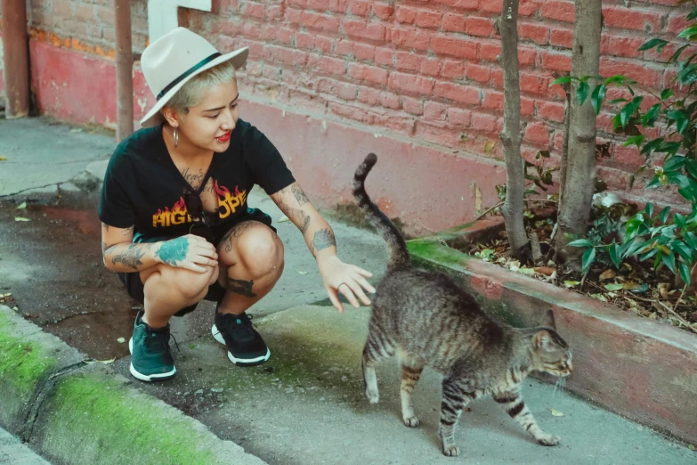 a woman kneeling down petting a cat on the sidewalk, by Julia Pishtar, pexels contest winner, sumatraism, an epic non - binary model, peruvian looking, he is a long boi ”, tattoo artist