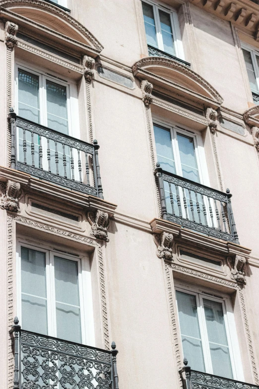 a tall building with lots of windows and balconies, inspired by François Girardon, trending on unsplash, art nouveau, light pink tonalities, directoire style, balcony door, grisaille