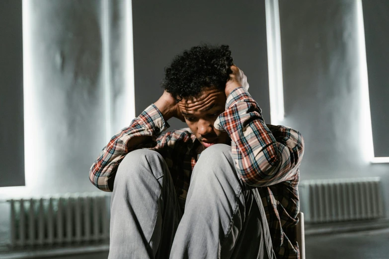 a man sitting on the ground with his head in his hands, pexels, renaissance, donald glover, ptsd, stood in a cell, heartbroken