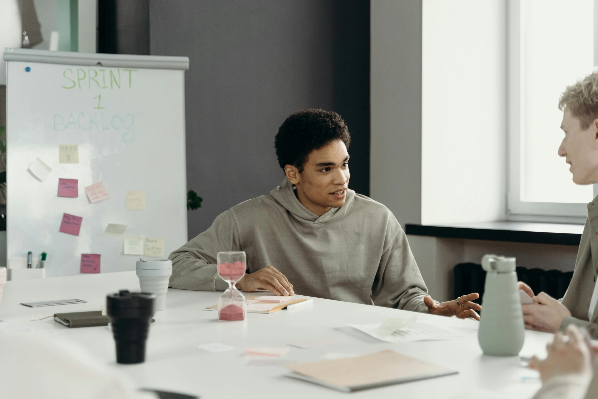 a group of people sitting around a white table, on a desk, young man, background image, lachlan bailey