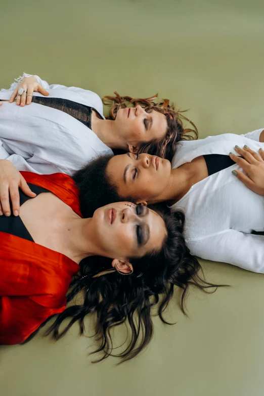 a group of women laying on top of each other, an album cover, trending on pexels, bauhaus, androgynous person, studio shoot, three moons, looking off to the side